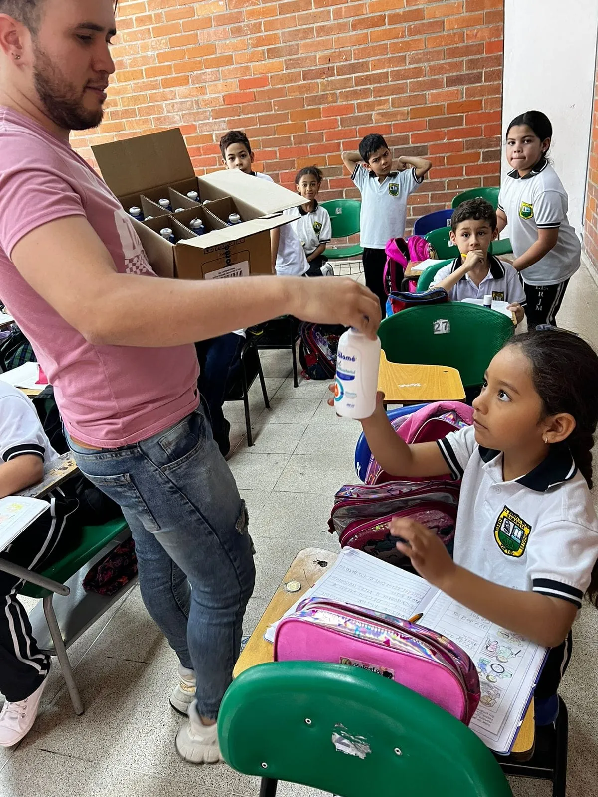 Una niña recibe un kit de aseo de un voluntario en el aula